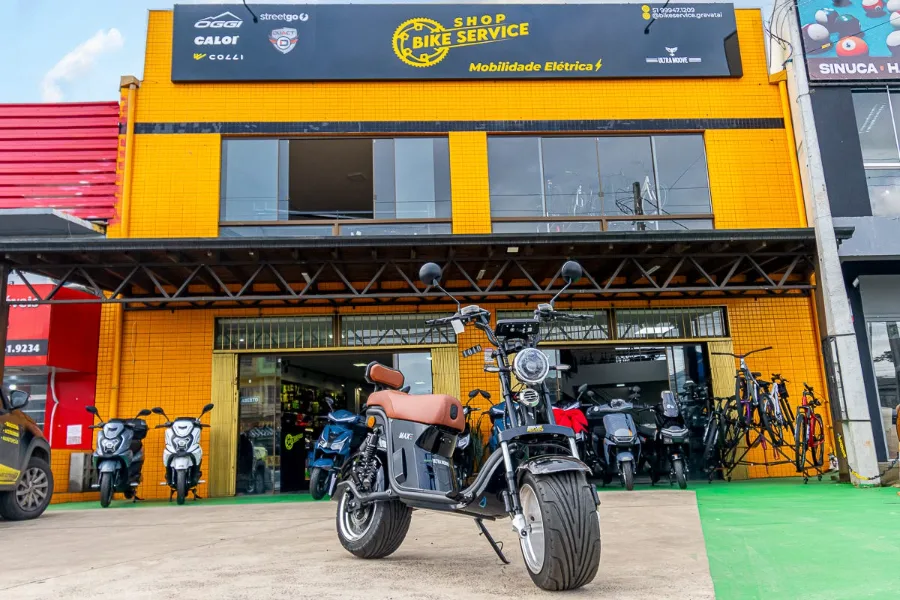 Fachada amarela da Bike Service com uma scooter elétrica na frente