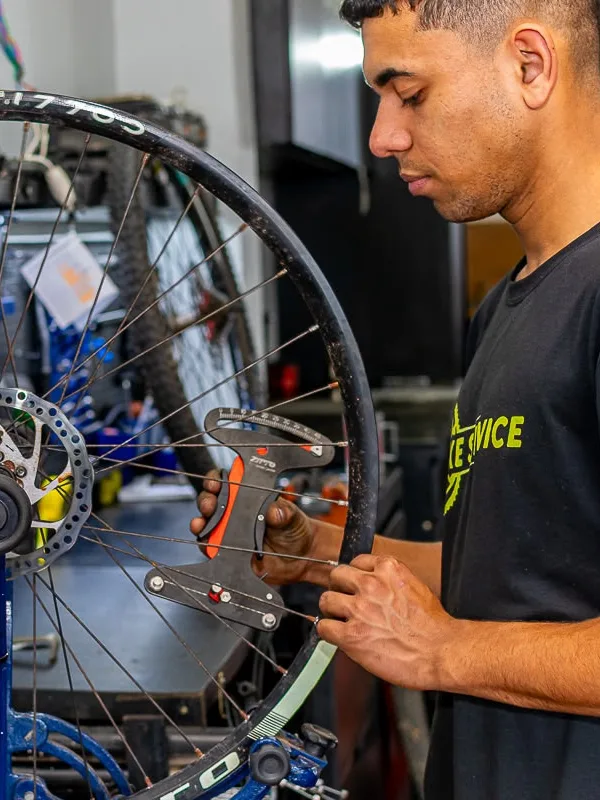 Mecânico alinhando a roda de uma bicicleta na oficina
